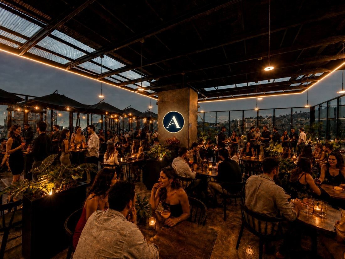 Terraza de Cora Rooftop de noche, con público y la ciudad de fondo